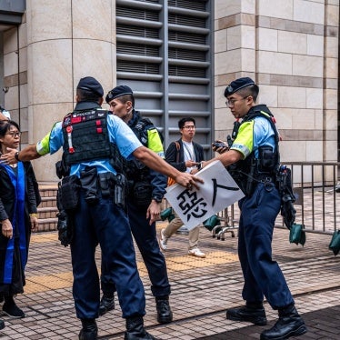 Police remove a sign from Elsa Wu, foster mother of activist Hendrick Lui