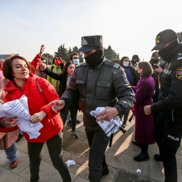 A woman holding a protest sign is surrounded by police