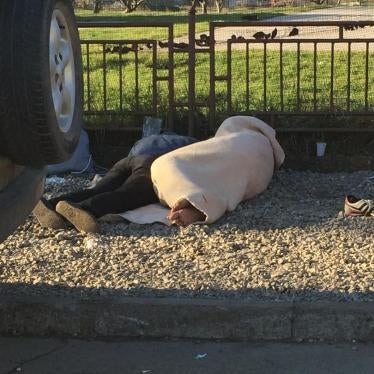 Two Afghan asylum seekers sleeping on the ground outside a registration camp in Dimitrovgrad, Serbia.