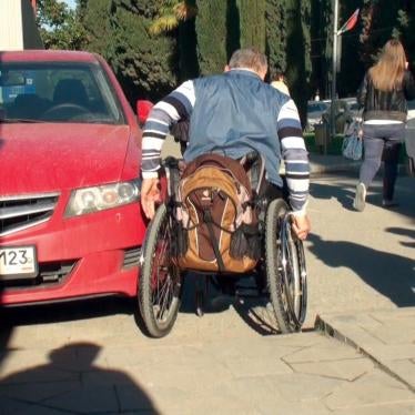 Alexander Simyonov navigates his wheelchair around a parked car in the Adler district of Sochi, February 8, 2013.