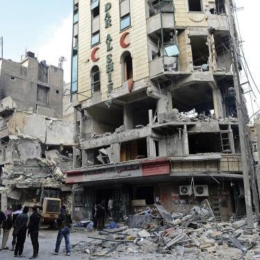 Syrian opposition fighters and bystanders watch bulldozers clean the debris outside Dar al-Shifa hospital in Aleppo, northern Syria, on November 22, 2012.