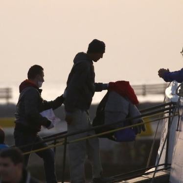 A Frontex officer (L) escorts a deportee onto a boat on the Greek island of Lesbos, April 4, 2016.