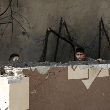 Afghan boys look out from behind a damaged wall after a Taliban attack in Kabul, Afghanistan October 6, 2015.