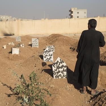 A family member stands next to the graves of three children who were killed when an explosive device planted by ISIS in a school in Manbij detonated on September 27.  