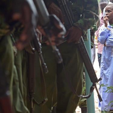 A picture of children looking at Kenyan police carrying guns.