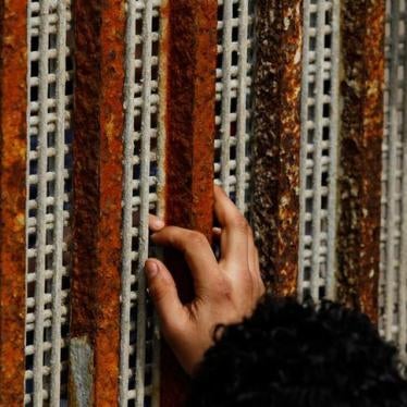 A man, who was deported from the U.S. seven months ago, touches the fingertips of his nephew across a fence separating Mexico and US.