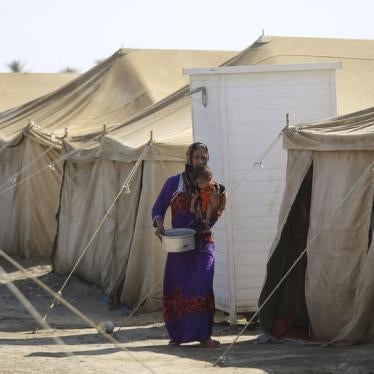 An Iraqi displaced woman, who fled from ISIS violence in Anbar, carries her child at a camp for displaced families camp in Amiriyat al-Fallujah, July 25, 2015. © 2015 