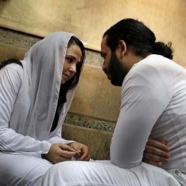 Aya Hegazy and her husband Mohamed Hassanein, founders of a nongovernmental organization that looks after street children, sit on the ground talking inside a holding cell as they face trial on charges of human trafficking, sexual exploitation of minors, a