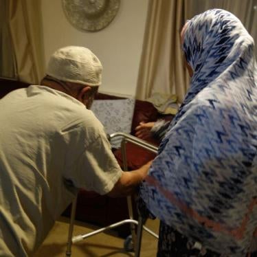 Farhaz is helped from his bed to the living room by his wife Barsha.  © 2018 Stephanie Hancock/Human Rights Watch