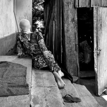 A girls with albinism seets on steps, she is seen from the back