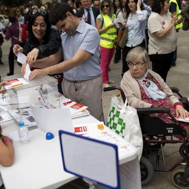 A man is helped to cast a symbolic vote during an event organized by The Spanish Committee of Representatives of Persons with Disabilities outside the Spanish parliament in Madrid, Friday, June 17, 2016.