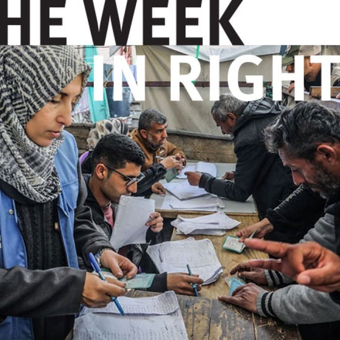 Group of individuals huddle over a table.
